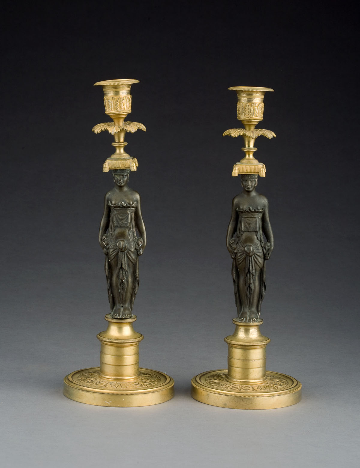 Appraisal: PAIR OF EMPIRE PATINATED AND GILT-BRONZE CARYATID-FORM CANDLESTICKS Each figure