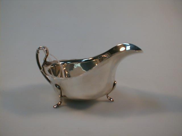 Appraisal: A silver sauce boat with a bracketed rim and strap