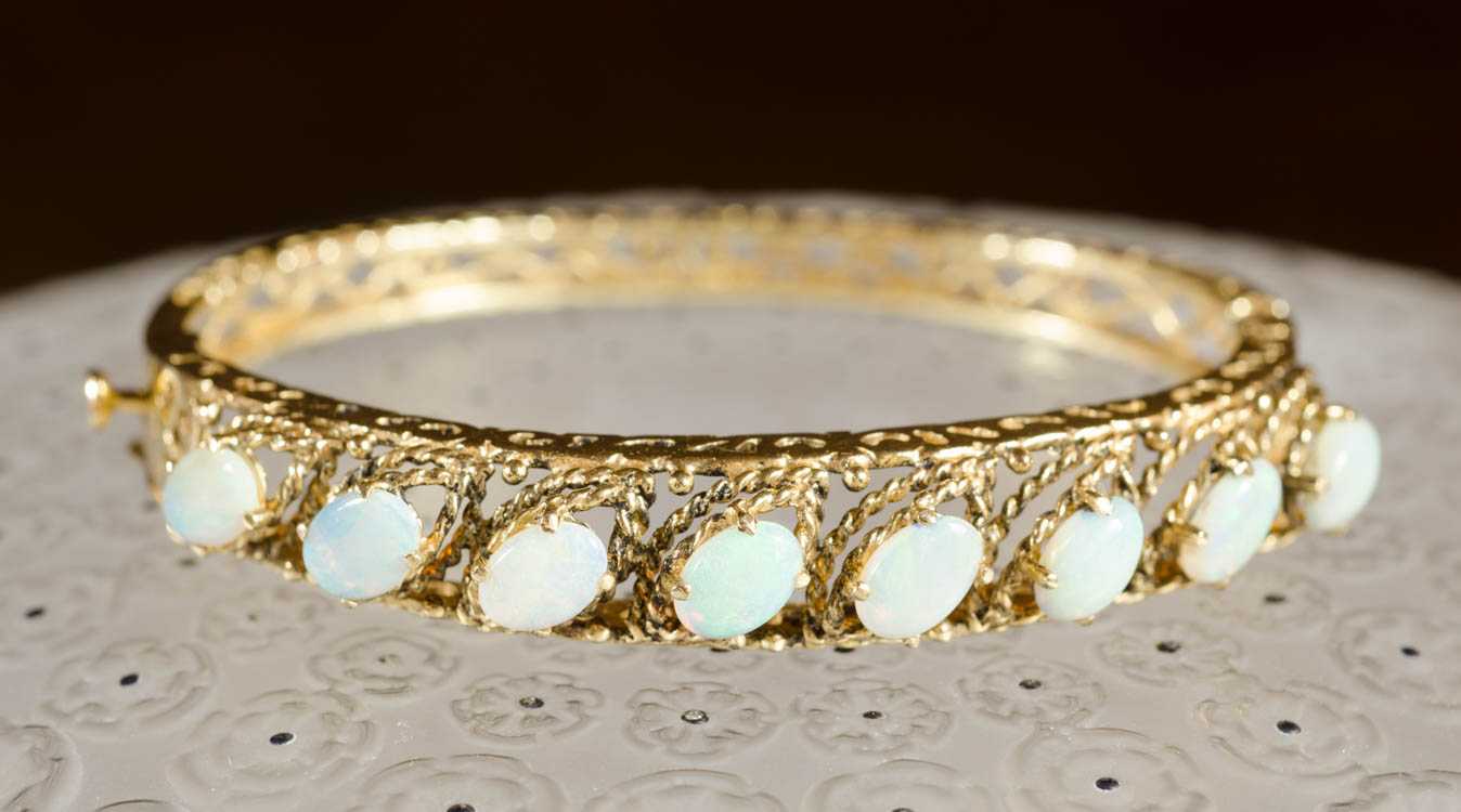 Appraisal: OPAL AND FOURTEEN KARAT GOLD BANGLE The oval hinged yellow