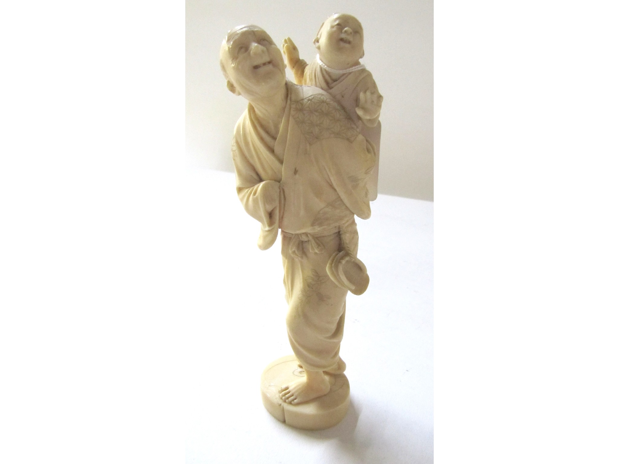 Appraisal: A Japanese carved ivory okimono - man with child some