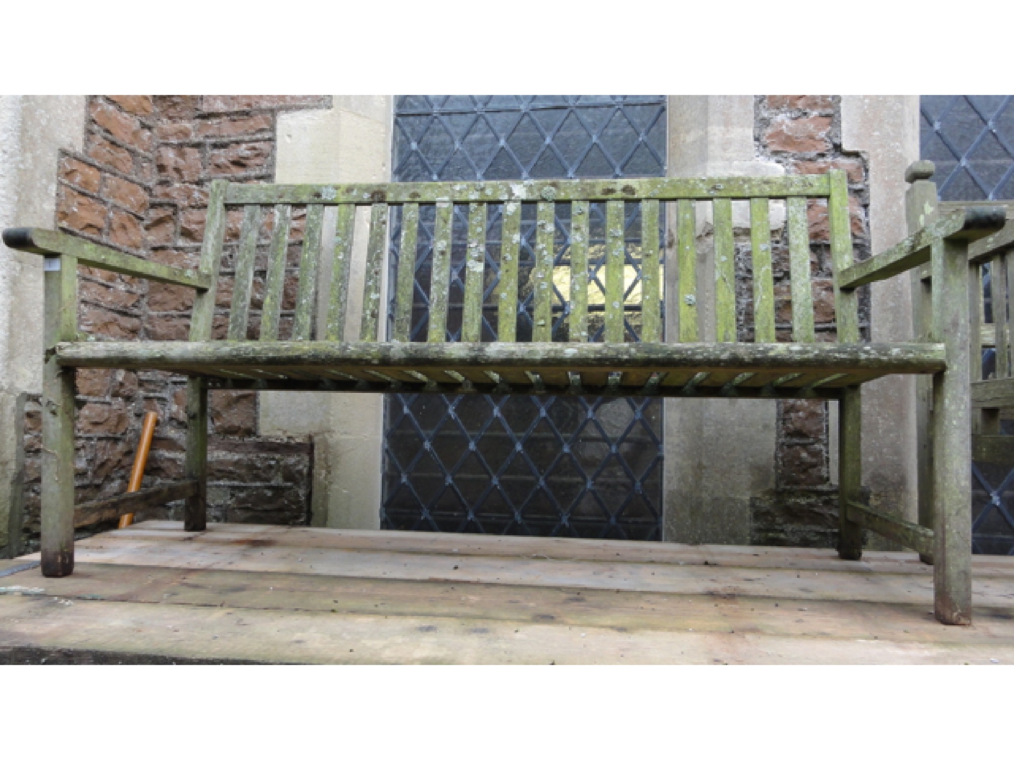 Appraisal: A weathered teak three seat garden bench with slatted seat