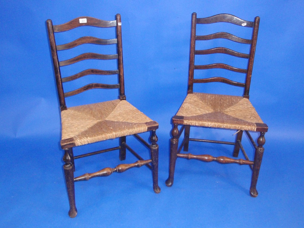 Appraisal: A pair of th century rush seated oak ladder-back chairs