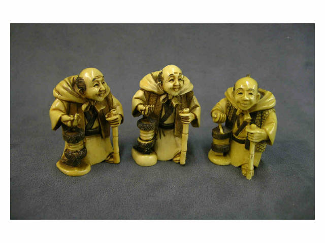 Appraisal: Three partially stained ivory netsuke depicting a man with a