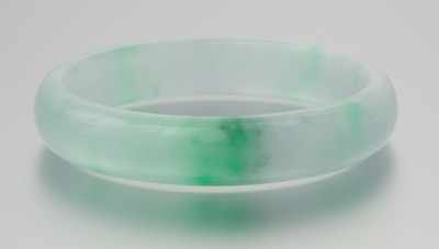 Appraisal: A Carved White and Green Jadeite Bangle Chinese A well-carved