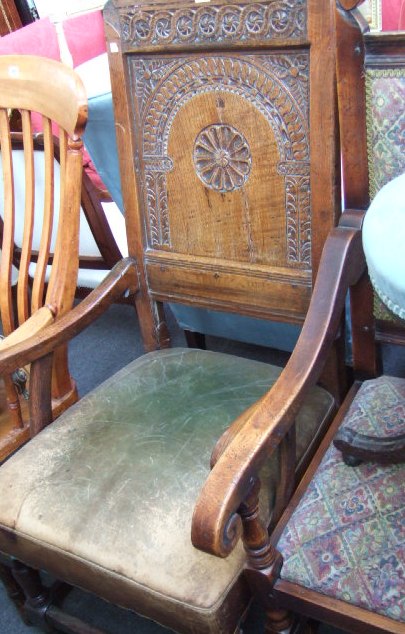 Appraisal: An oak armchair with carved back panel and leather straw