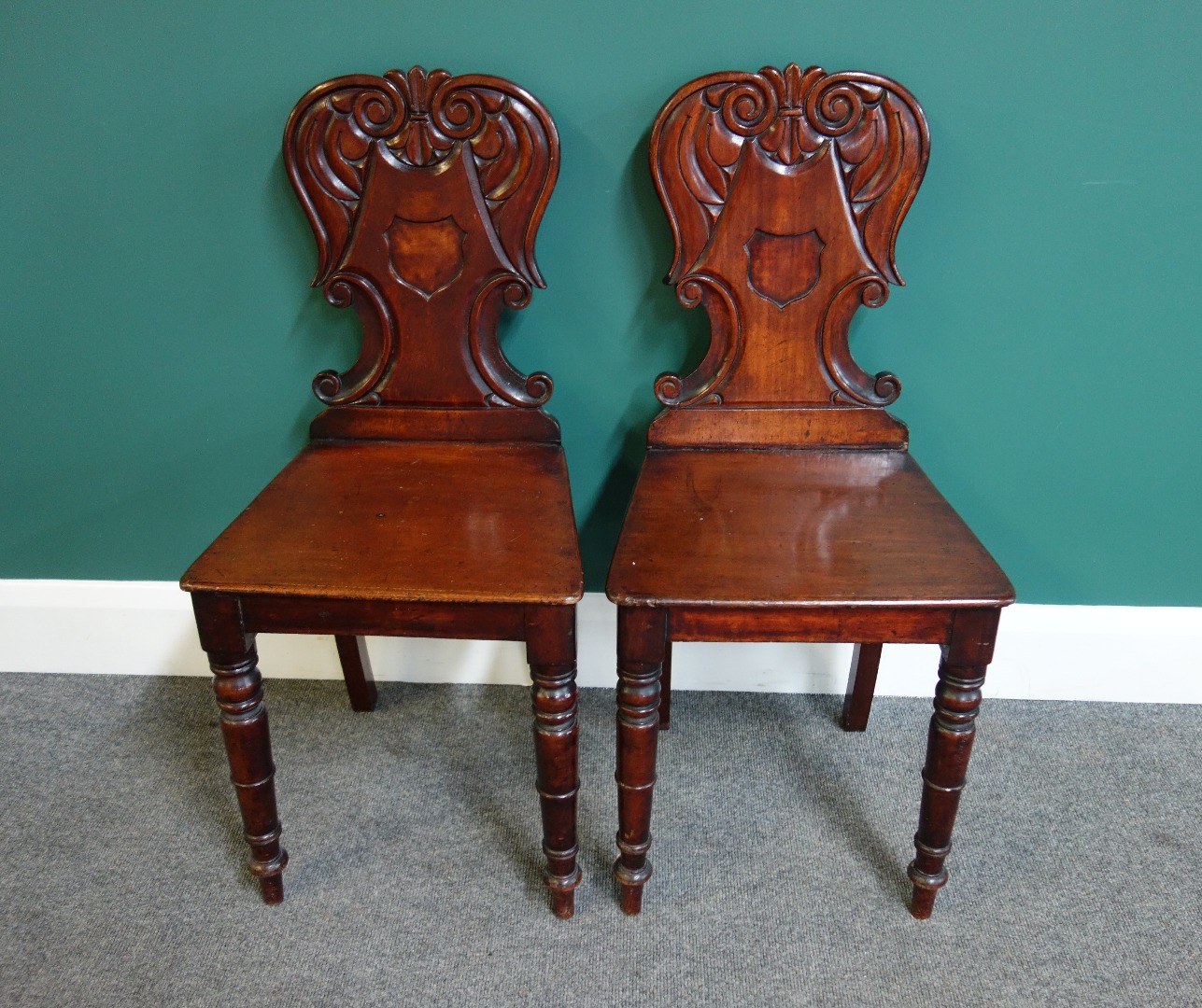 Appraisal: A pair of Victorian mahogany hall chairs with shield centred