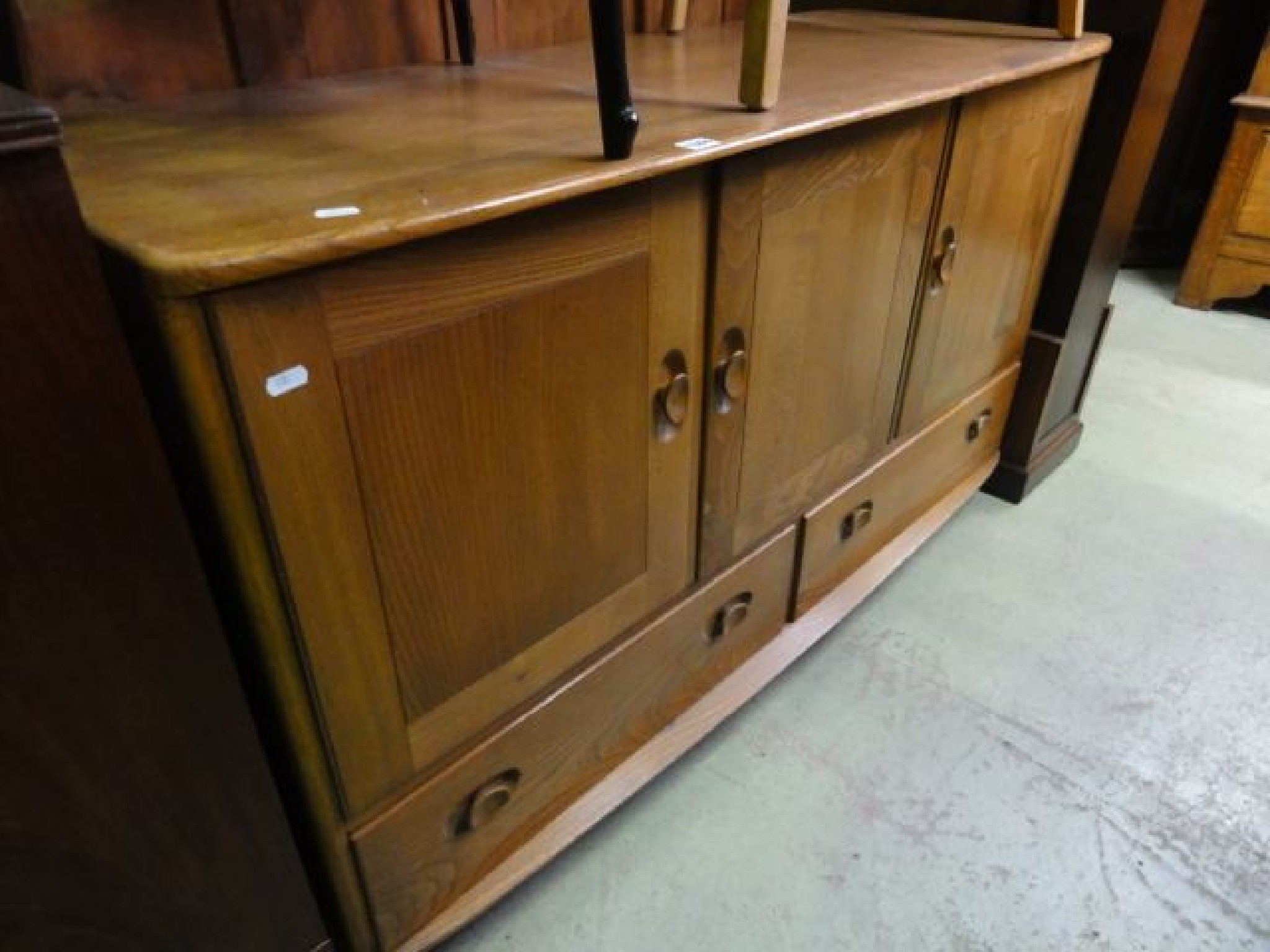 Appraisal: An Ercol medium to light elm sideboard partially enclosed by