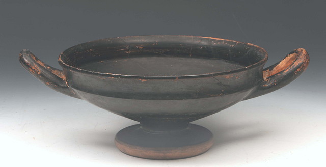 Appraisal: AN ANCIENT GREEK KYLIX of shallow form with loop handles