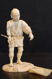 Appraisal: A JAPANESE IVORY OKIMONO STANDING MALE WITH GARDEN FORK