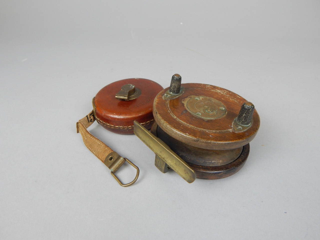 Appraisal: A mahogany and brass mounted fishing reel and a leather