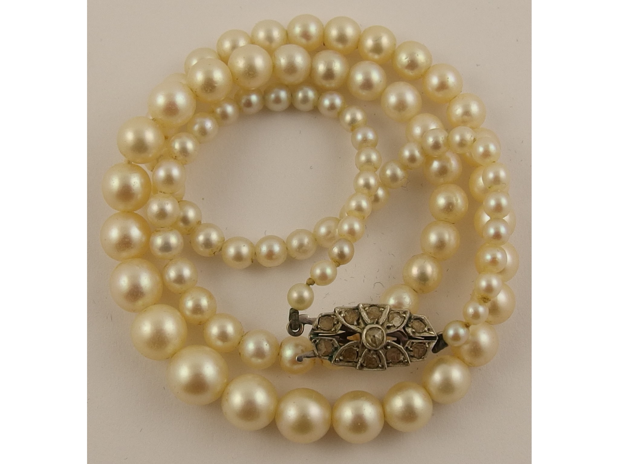 Appraisal: A string of cultured pearls with a white metal diamond