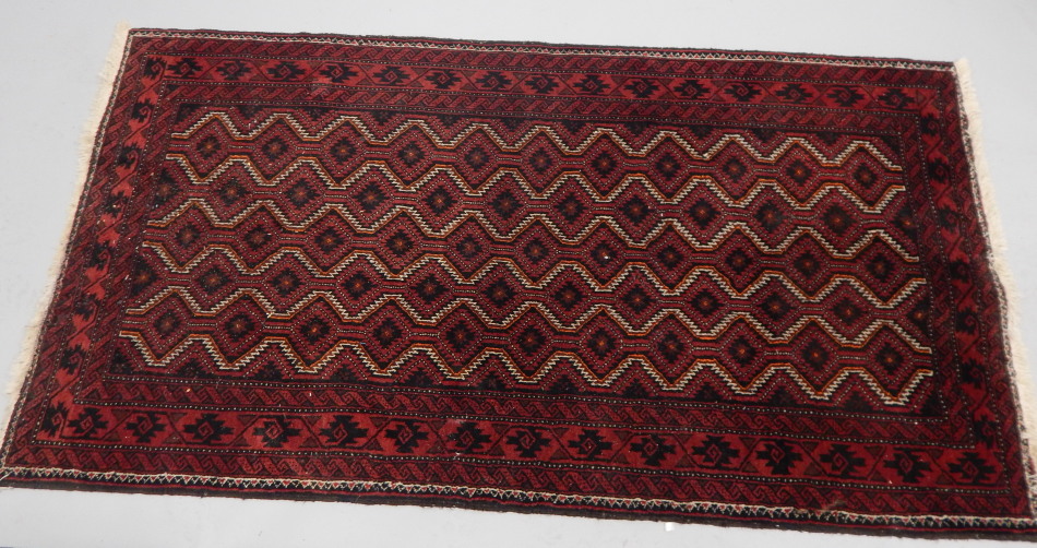 Appraisal: A Geometric rug of Persian design on a red ground