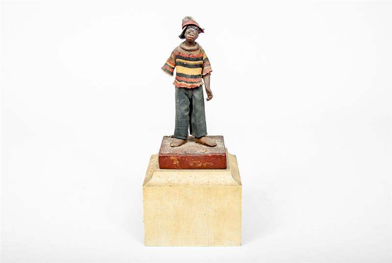 Appraisal: Fabric-Covered Pottery Figure of a Boy Wearing a hat jersey