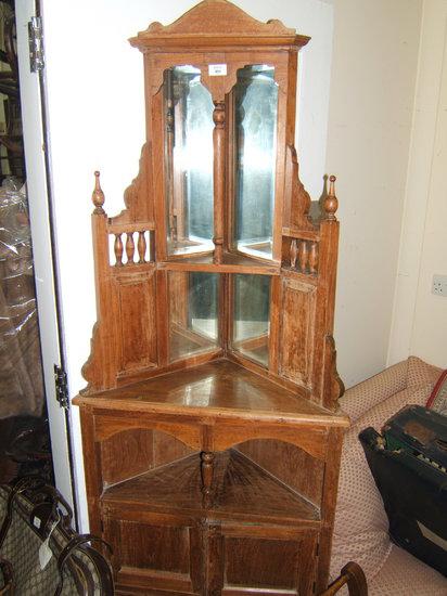 Appraisal: An Oriental hardwood corner display cabinet with raised mirror back