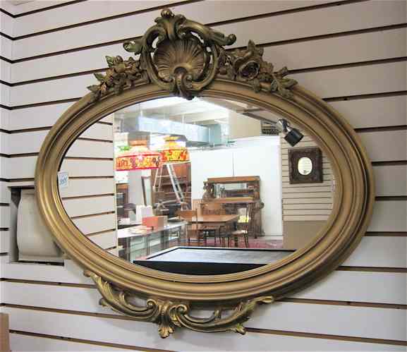 Appraisal: AN AMERICAN OVAL GILT WOOD FRAMED WALL MIRROR having shell