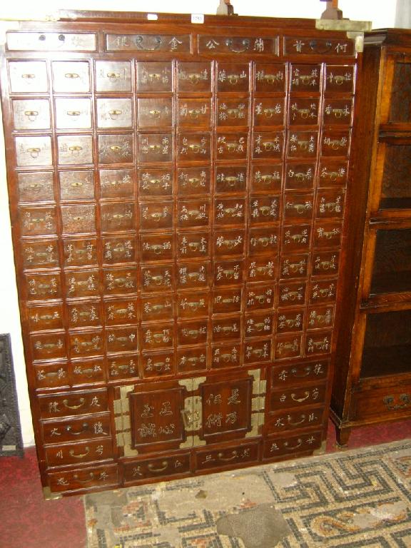 Appraisal: An eastern stained elm apothecary spice cabinet fitted with numerous