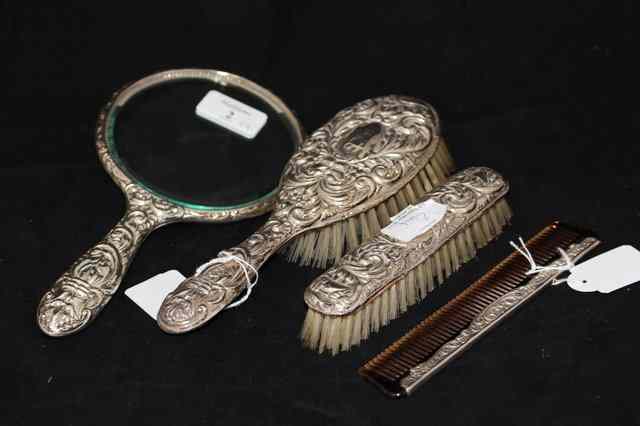 Appraisal: A SILVER BACKED HAND MIRROR together with two matching brushes