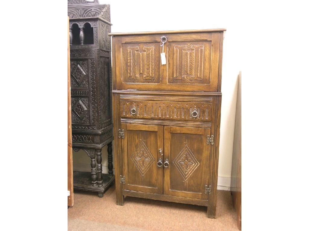 Appraisal: A dark oak cocktail cabinet linenfold fall front enclosing interior