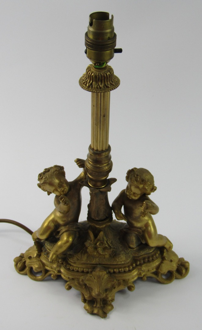 Appraisal: A gilt metal table lamp cast with putti on a