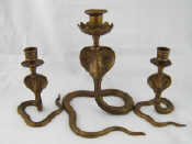 Appraisal: A group of three black enamelled brass cobra candlesticks a