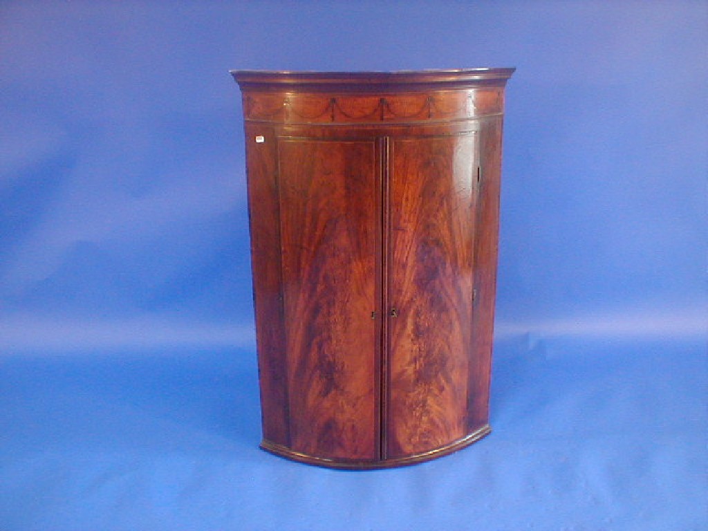 Appraisal: A George III figured mahogany cylinder fronted hanging corner cupboard