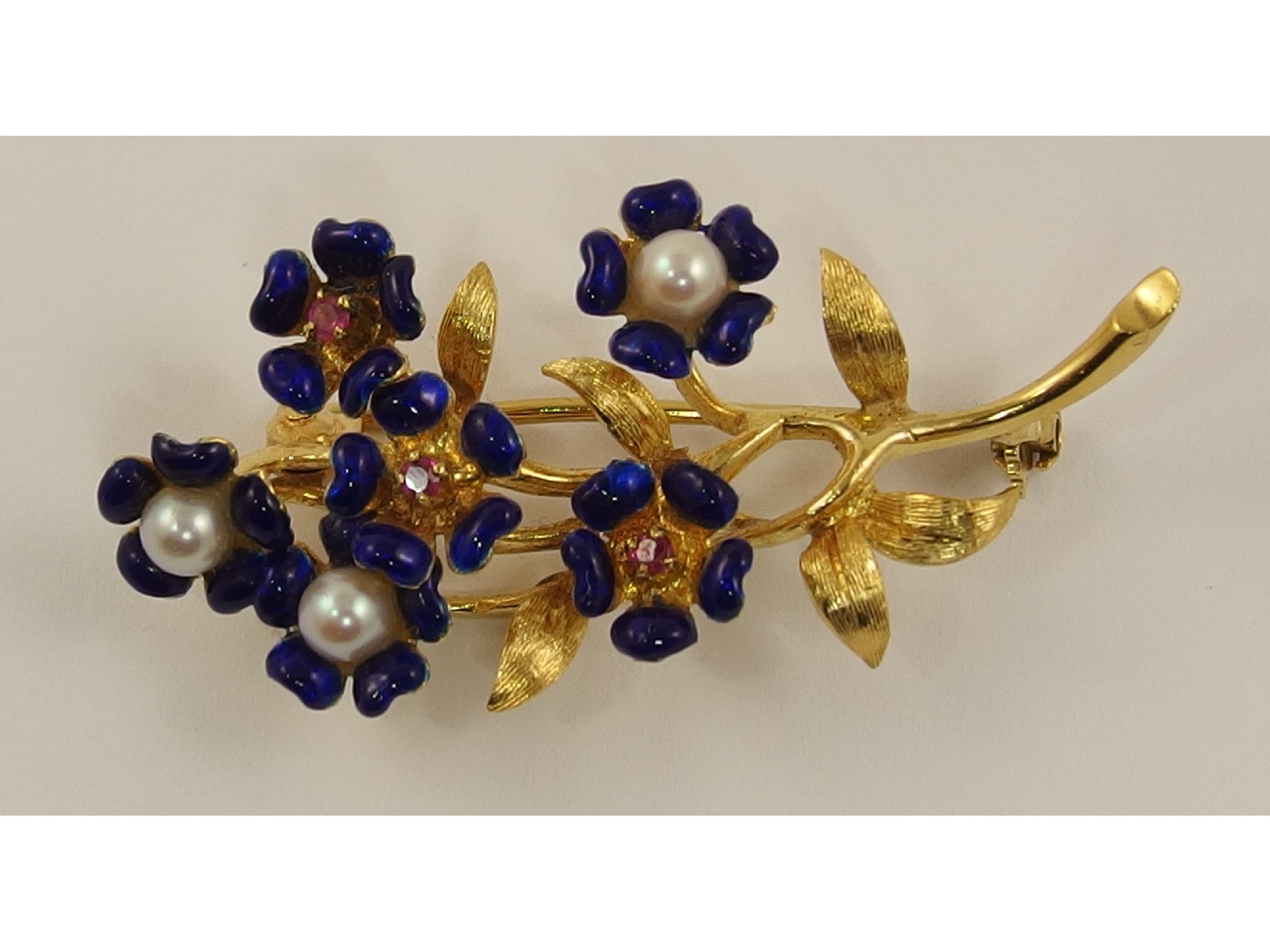 Appraisal: A yellow metal brooch with blue enamelled flowers the centres