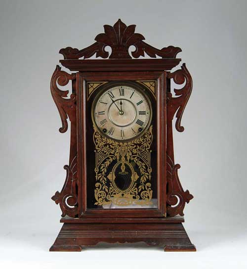 Appraisal: WALNUT GINGERBREAD CLOCK Carved scroll decorated standard form shelf clock