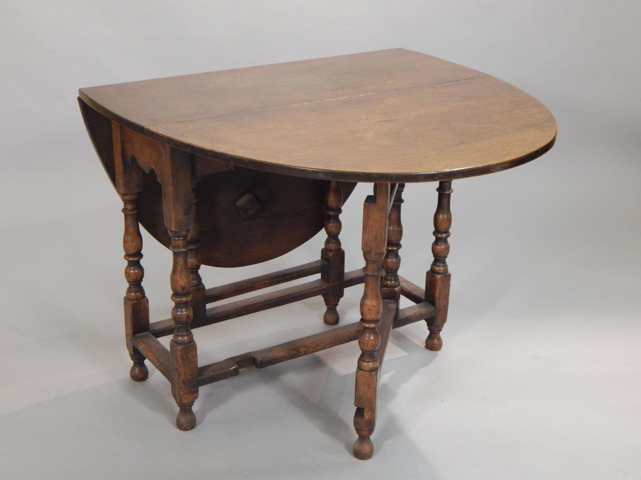 Appraisal: An oak gate leg table the oval top on turned