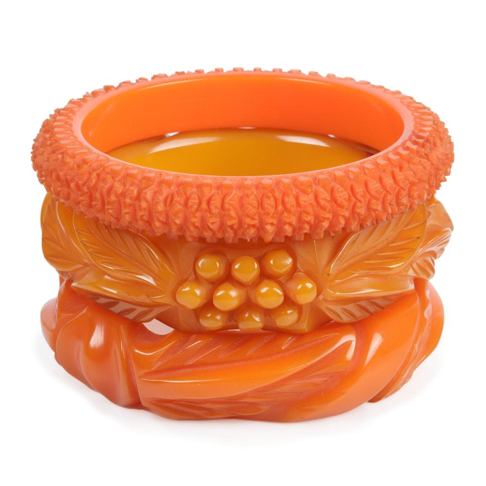 Appraisal: THREE DEEPLY CARVED BAKELITE BANGLE BRACELETS IN SHADES OF ORANGE