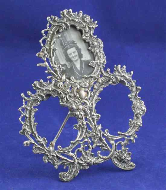 Appraisal: An Edwardian silver triple aperture photograph frame with pierced foliate