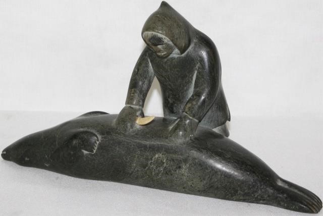 Appraisal: INUIT STONE CARVING DEPICTING A MAN STANDING OVERA SEAL HOLDING