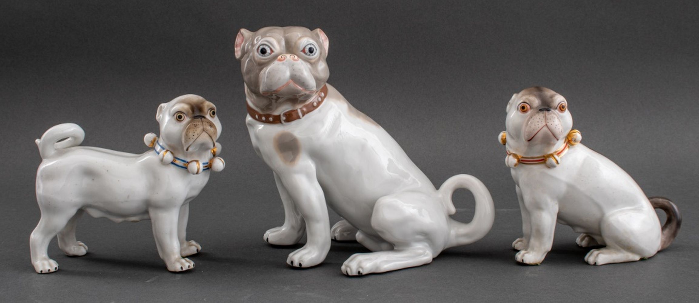 Appraisal: PORCELAIN PUGS FIGURINE Group of three porcelain figurines depicting pugs