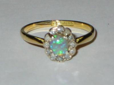 Appraisal: AN OPAL AND DIAMOND CLUSTER RING the oval cabochon opal