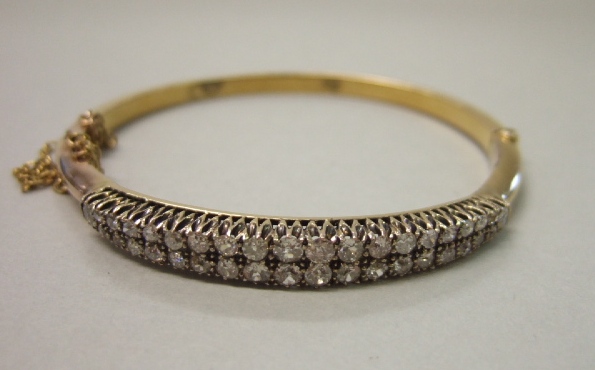 Appraisal: A gold and diamond set oval hinged bangle the front