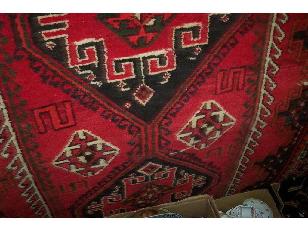 Appraisal: A red ground Iranian wool rug with hooked and geometric