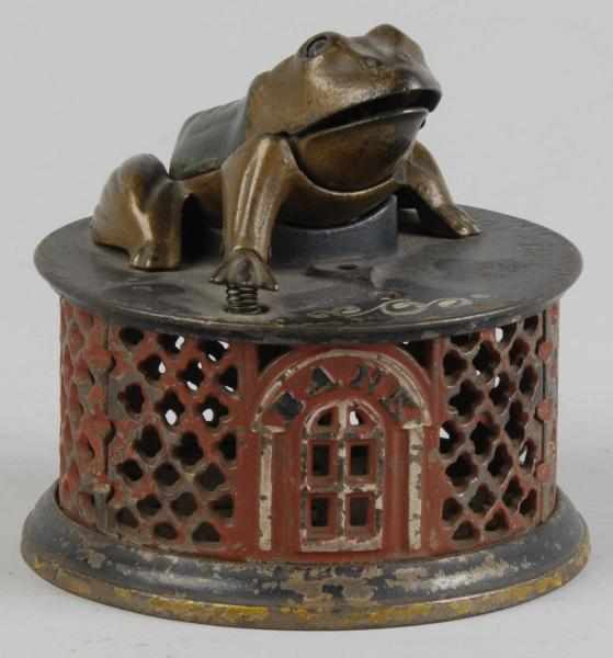 Appraisal: Cast Iron Frog on Lattice Mechanical Bank Description Manufactured by