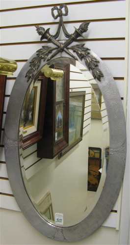 Appraisal: AN OVAL-SHAPED BEVELED WALL MIRROR having a hammered aluminum covered