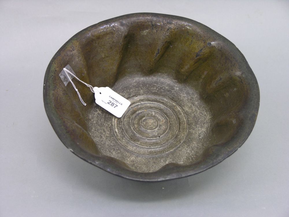 Appraisal: A primitive green glazed dish spiral moulded with concentric device