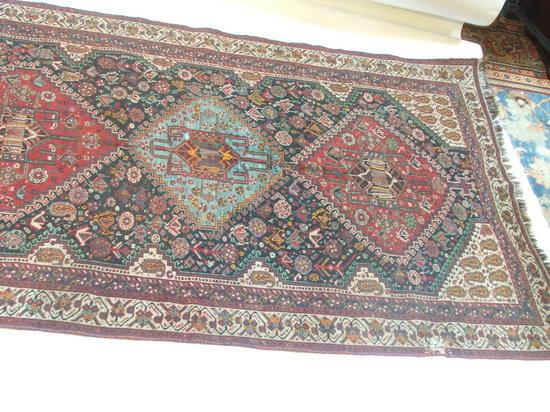 Appraisal: A SHIRAZ RED GROUND RUG decorated central triple medallion within