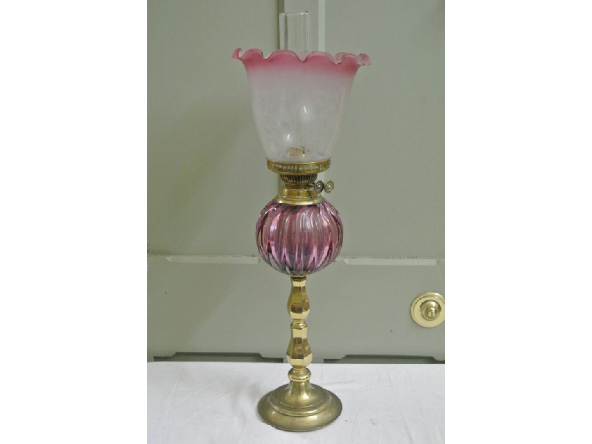 Appraisal: A vintage brass oil lamp with cranberry tinted melon shaped