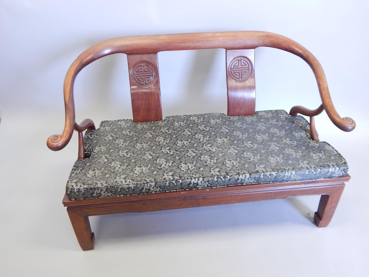 Appraisal: An Oriental hardwood sofa with a shaped back two carved