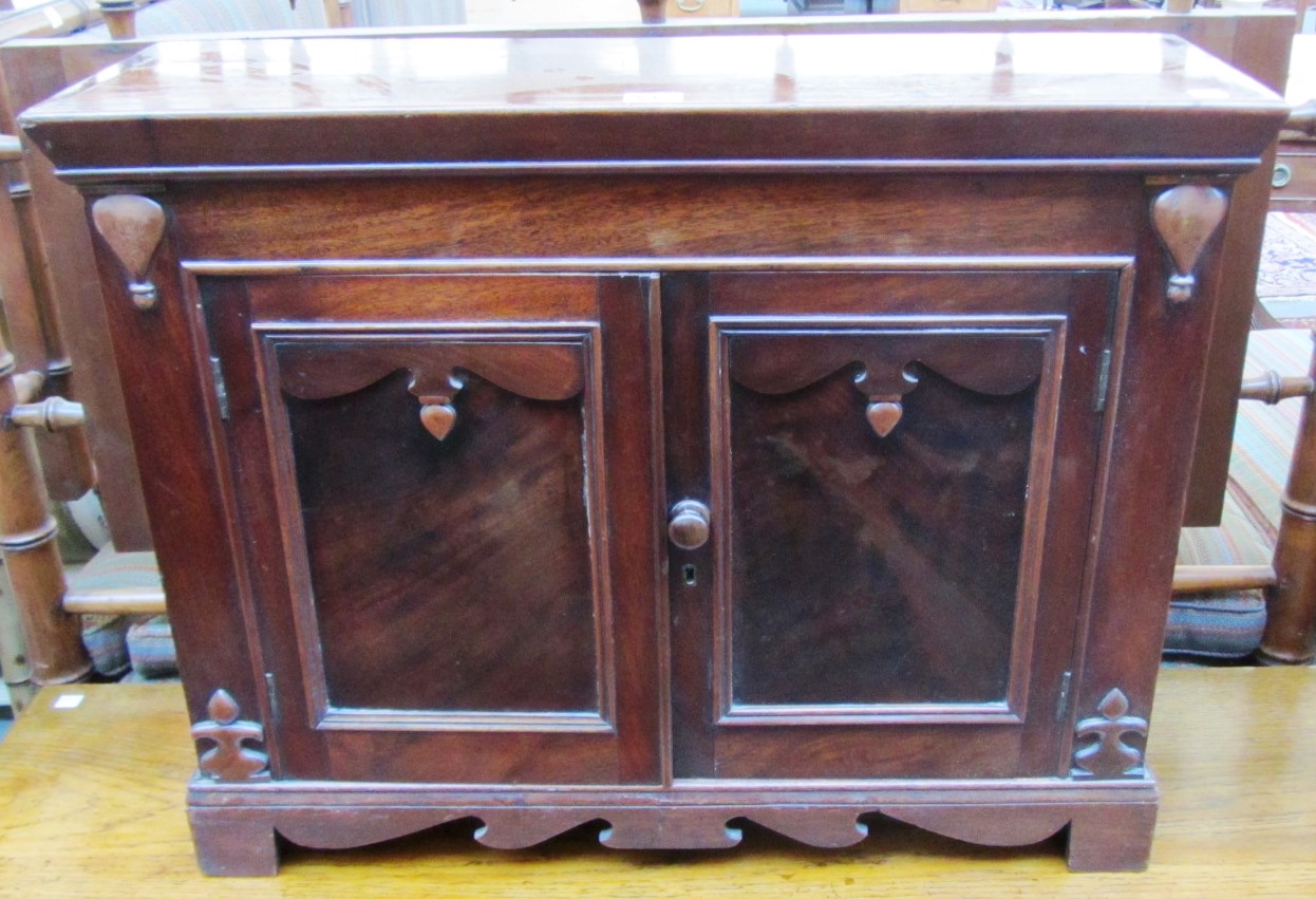 Appraisal: A small mahogany two door cupboard with shaped frieze and