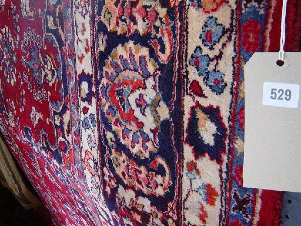 Appraisal: A red ground heavy Eastern wool carpet with stylised floral