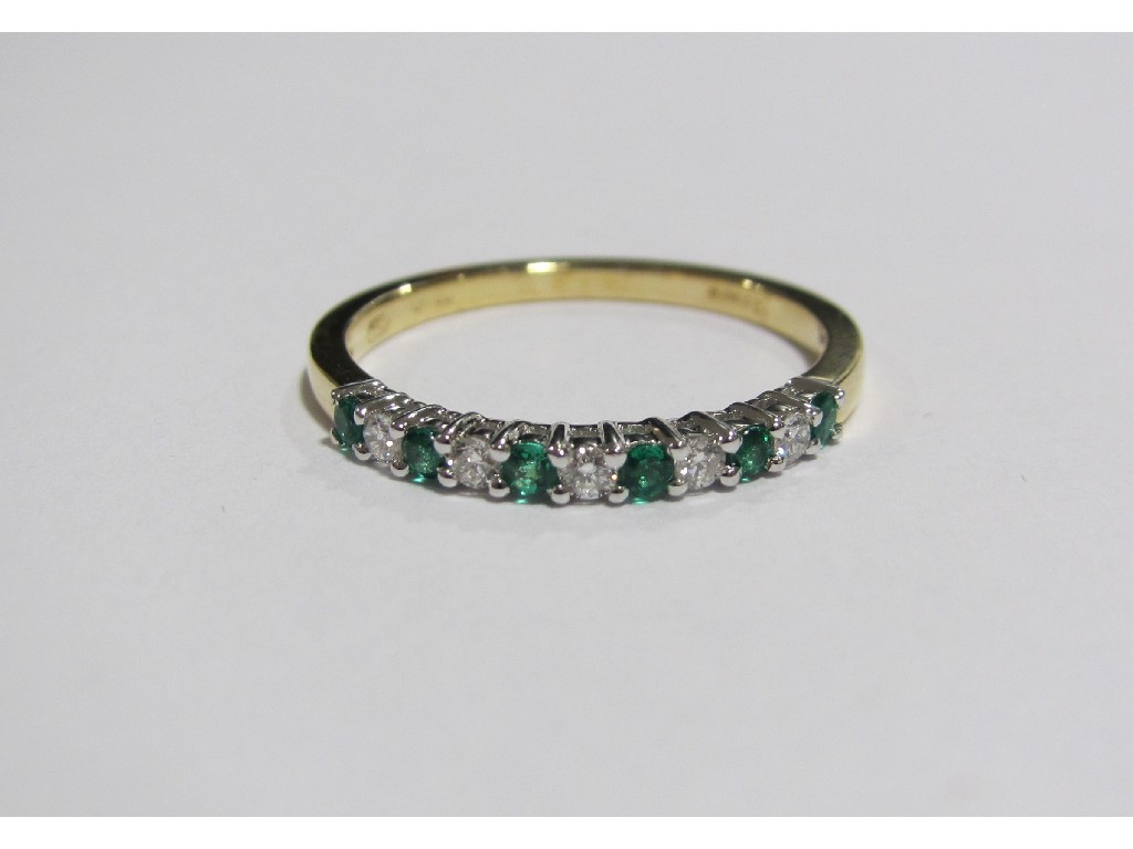 Appraisal: An eighteen carat gold emerald and diamond half hoop ring