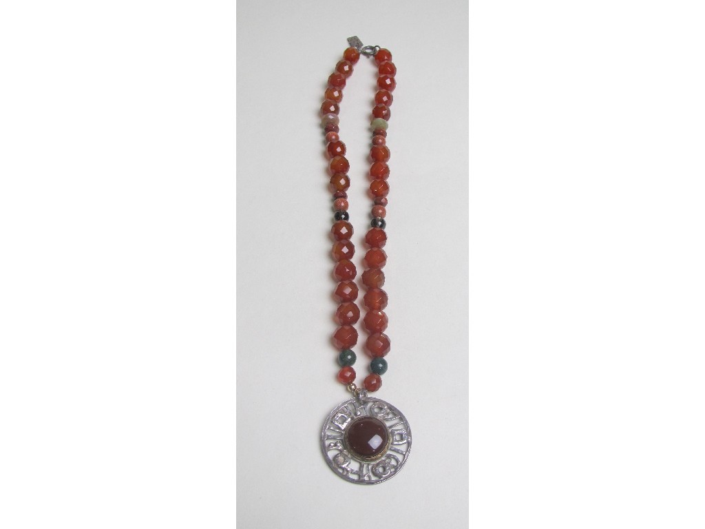 Appraisal: String of faceted cornelian beads with pierced silver circular pendant