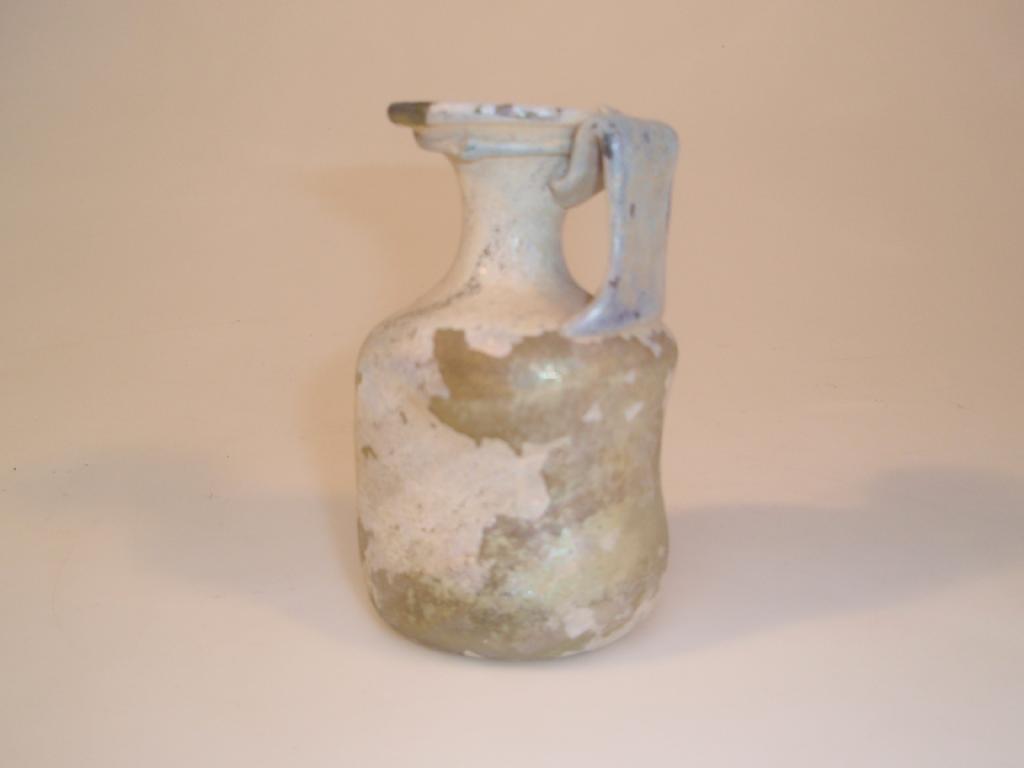 Appraisal: A fire-damaged Roman cylindrical jug made in yellowish-green glass possibly