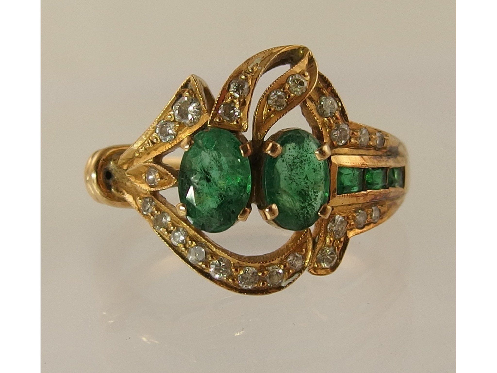 Appraisal: An emerald and diamond dress ringthe yellow metal asymmetrical design