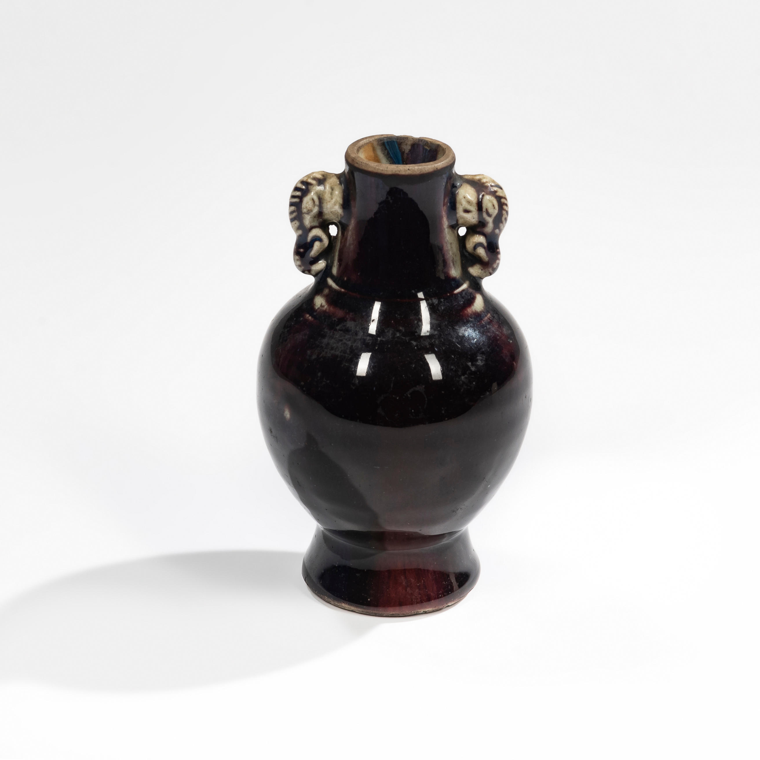 Appraisal: AUBERGINE-GLAZED FOOTED VASE China Ming-style hu -form with elephant handles