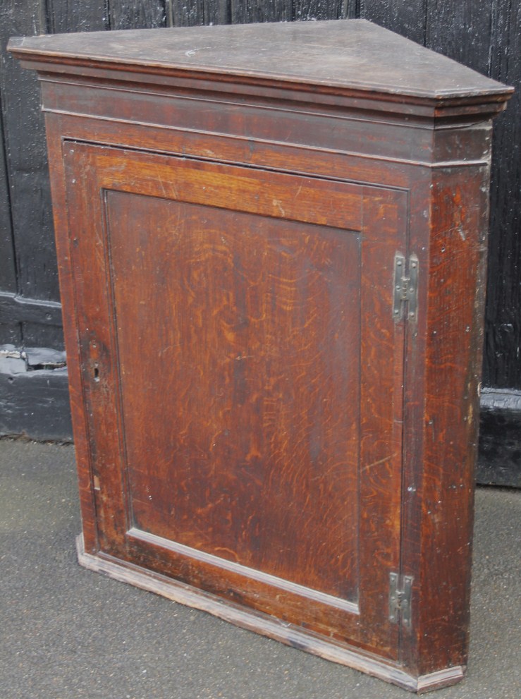 Appraisal: An early thC oak hanging corner cupboard with plain door