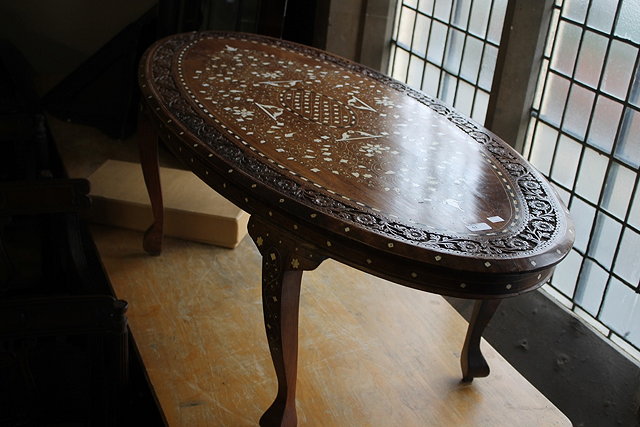 Appraisal: A CHINESE STYLE OVAL COFFEE TABLE inlaid with ebony and